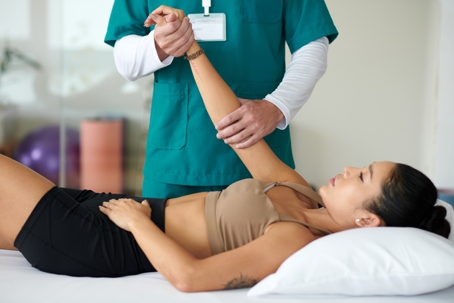 Woman having her arm examined by a physical therapist for chronic pain.